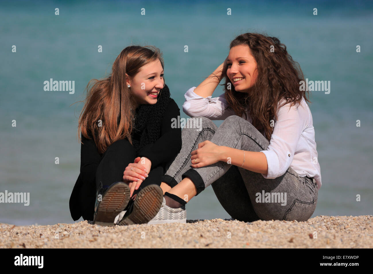 Dos amigas, adolescentes, sentado en la playa, Menton Alpes Marítimos, Provenza Alpes, Francia Foto de stock