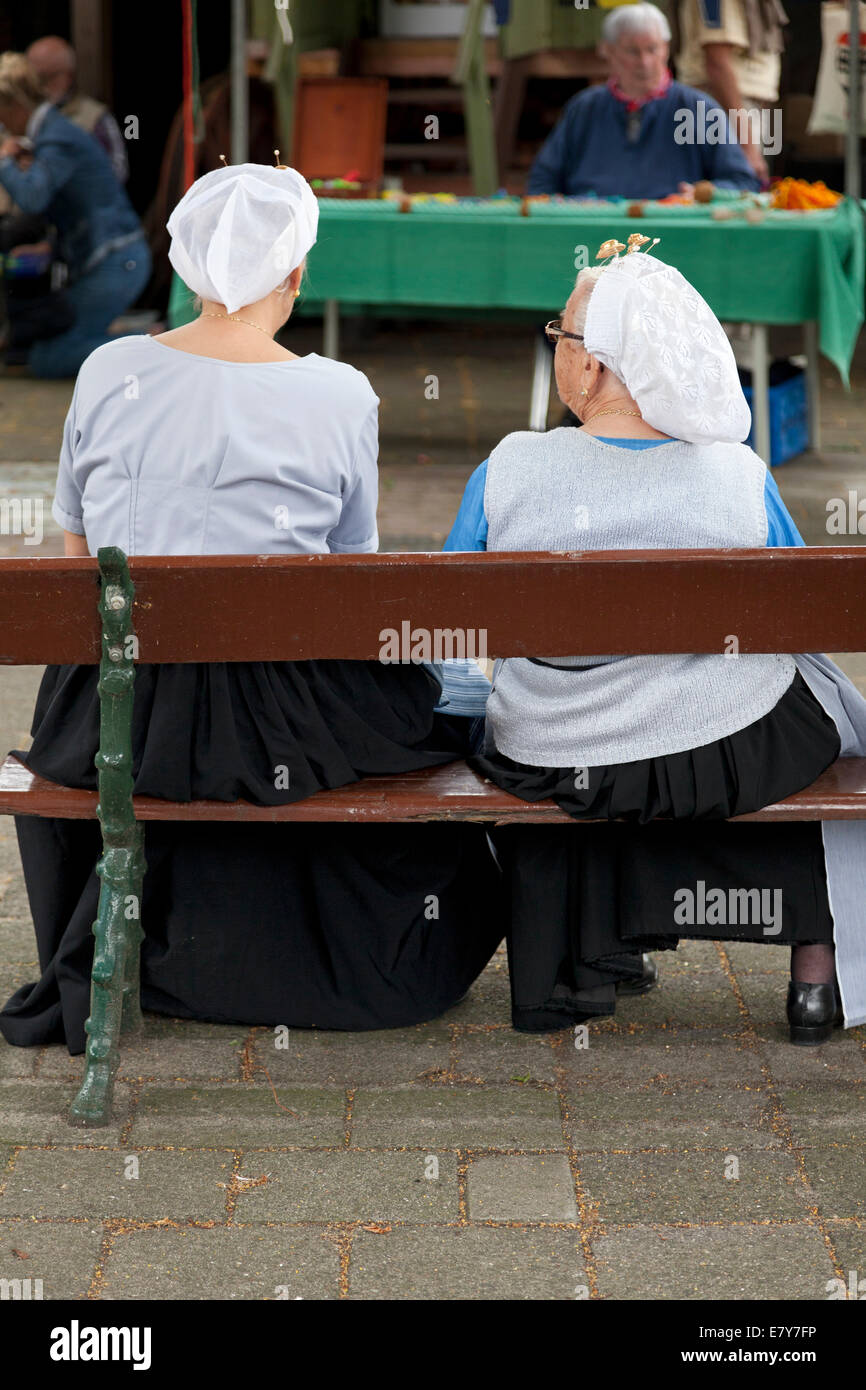 Mujer en trajes tradicionales de scheveningen sentado en un banco Foto de stock