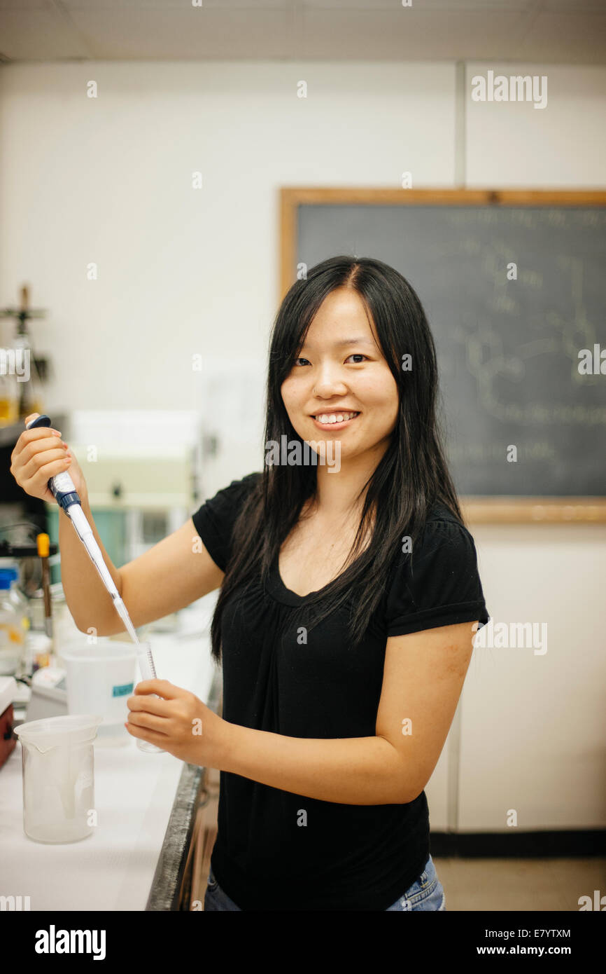 Mujer en laboratorio con pipeta y tubo de vidrio de llenado Foto de stock