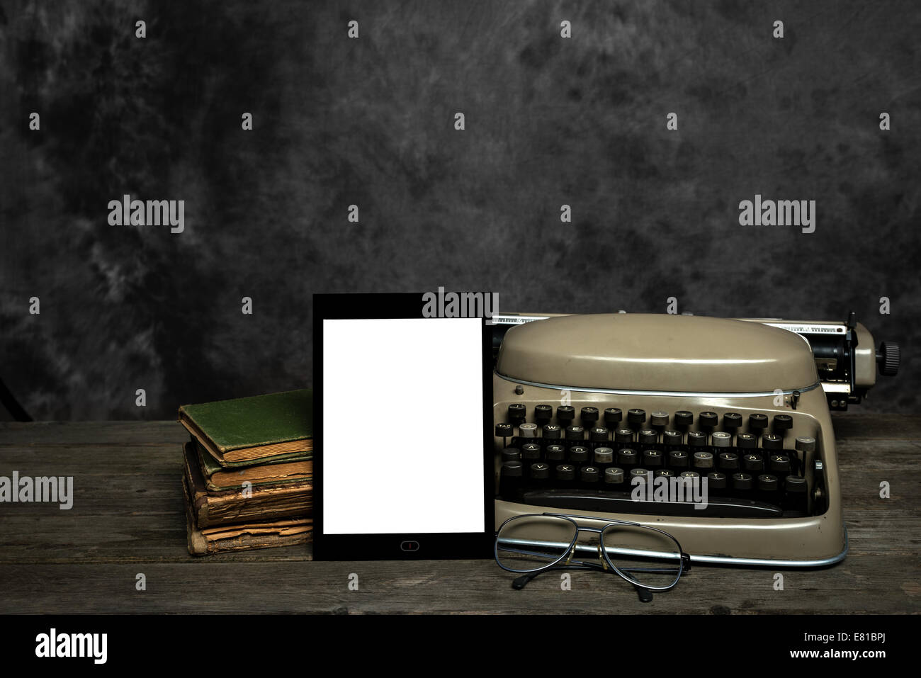 Antigua máquina de escribir, libros antiguos, gafas de lectura y un diseño propio E-Reader con pantalla en blanco Foto de stock