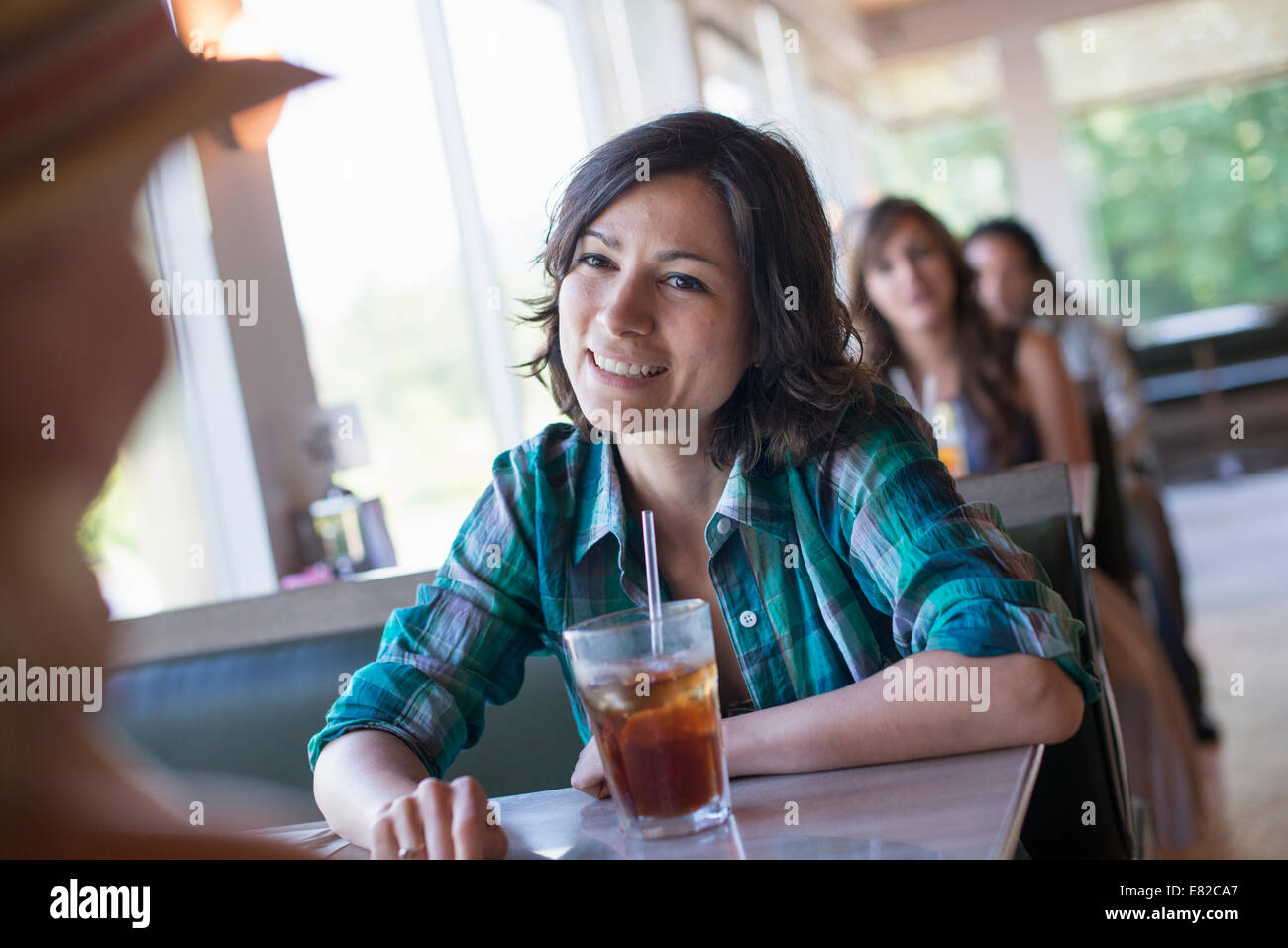 Una mujer sentada en un comedor mirando a su compañero. Un largo trago refrescante con una paja. Foto de stock