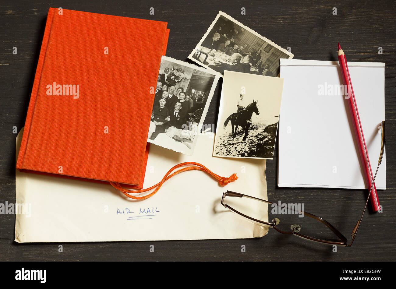 La historia de la familia, la investigación genealógica, antiguas fotografías desde la Segunda Guerra Mundial, el correo aéreo, libro rojo, el Bloc de notas con lápices de colores y gafas de lectura Foto de stock