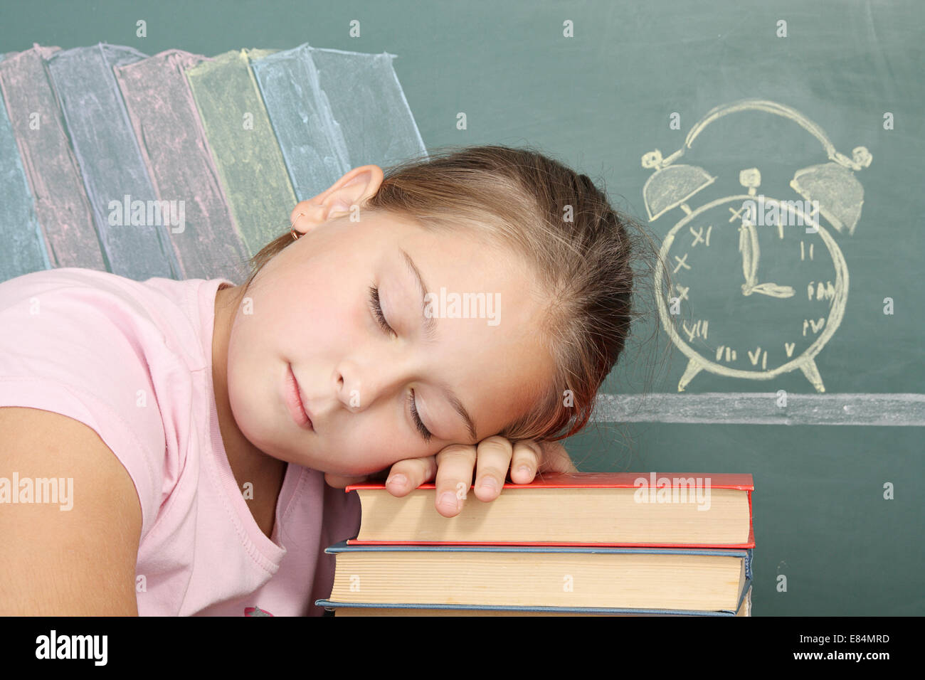 Cansado schoolgirl dormido sobre libros de texto Foto de stock