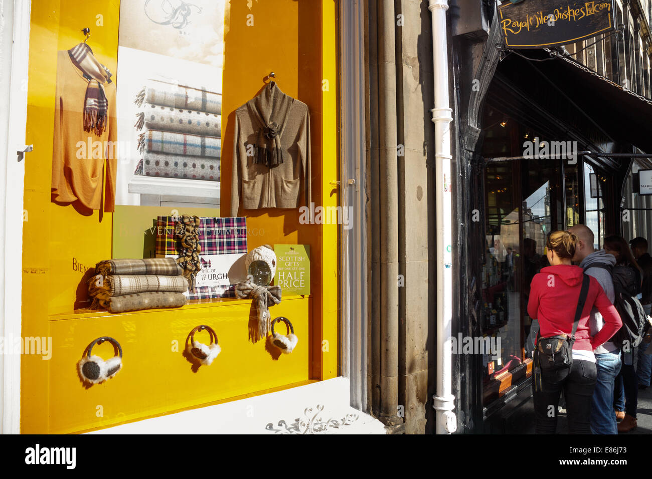 Pareja joven busca en una tienda escaparate en la Royal Mile de Edimburgo, Casco antiguo Foto de stock
