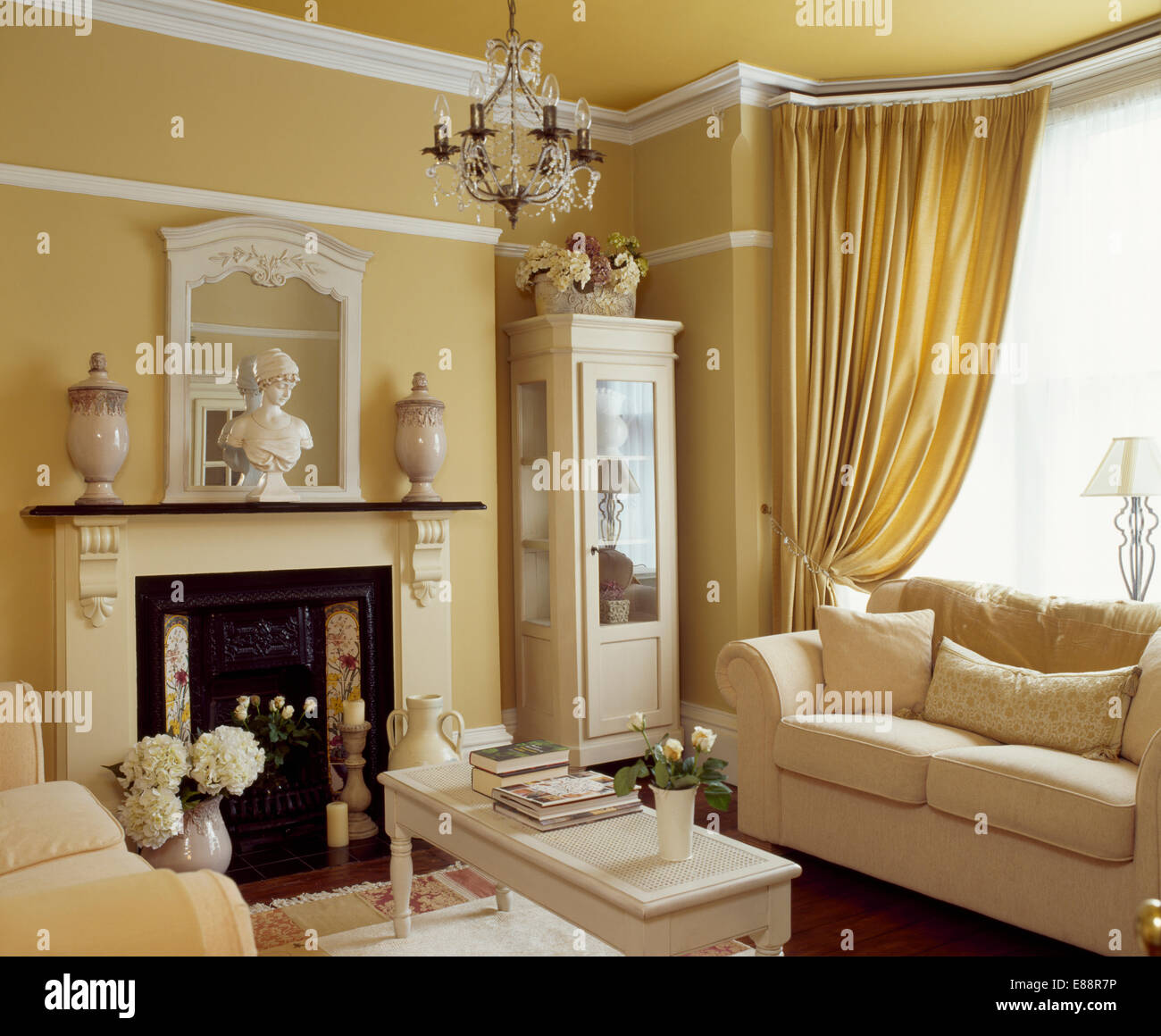 Crema sofá delante de una ventana con cortinas en crema de color paja.  Salón con chimenea crema Fotografía de stock - Alamy