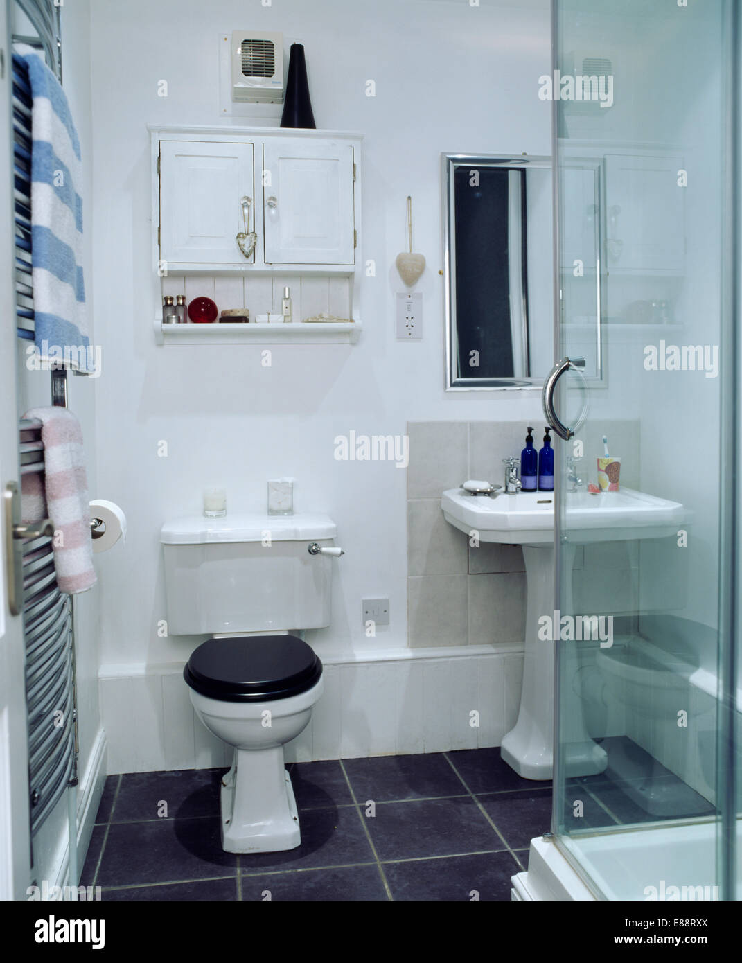 Armario de pared blanco pequeño encima de WC en el pequeño cuarto de baño  moderno con ducha de cristal gabinete Fotografía de stock - Alamy