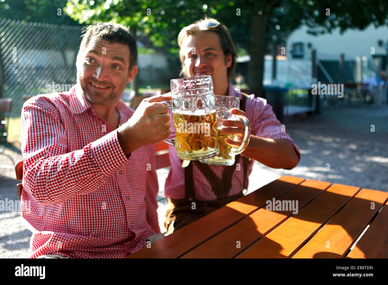 Dos bávaros sentado en un jardín de cerveza y bebidas smb.'s Health Foto de stock