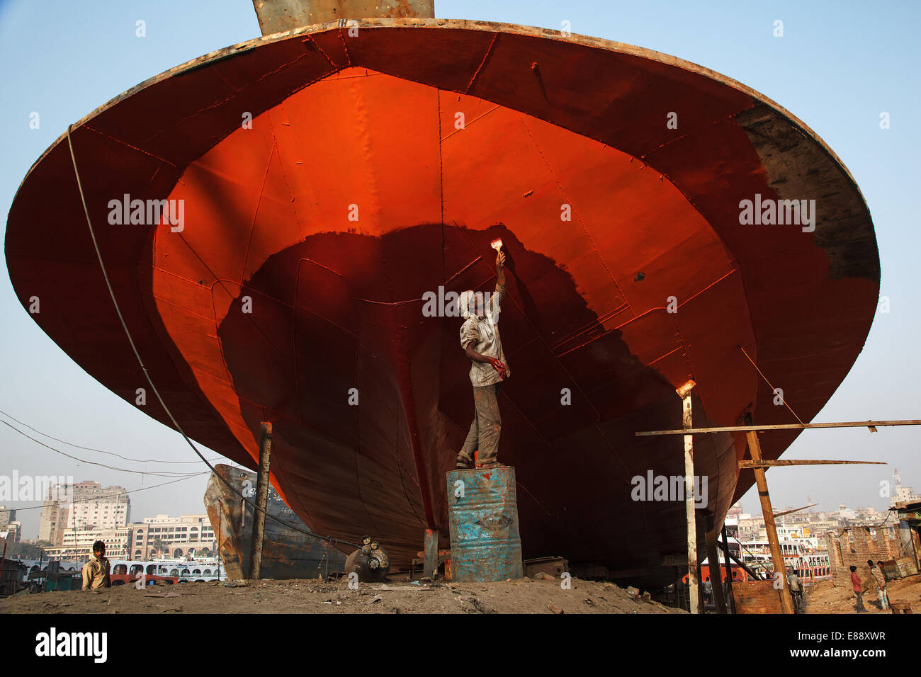 Un trabajador pintar un barco grande con un pincel en el astillero de Río Buriganga en Dhaka, Bangladesh. Foto de stock