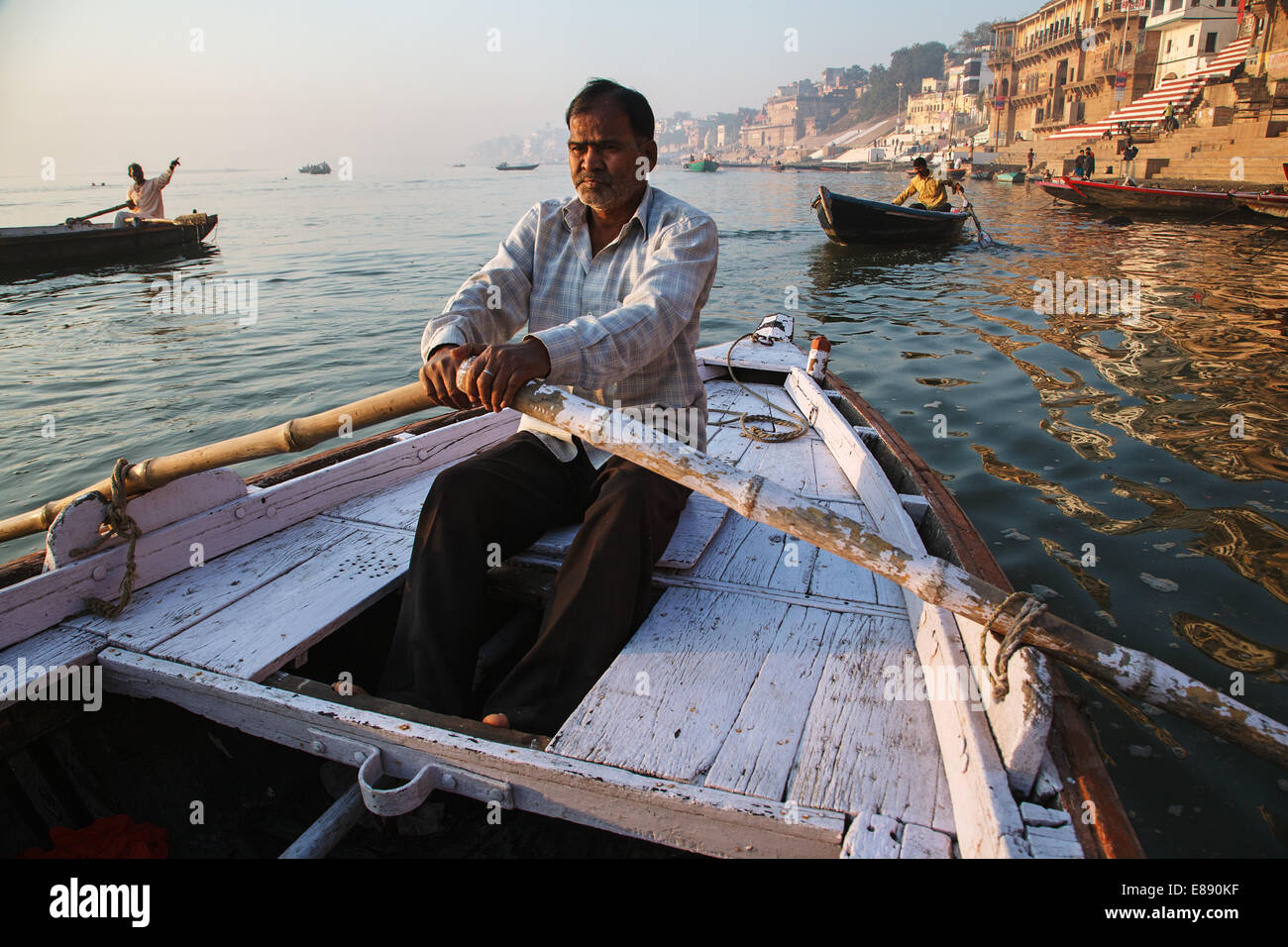 Un barquero filas un barco en el río Ganges en Varanasi, India. Foto de stock