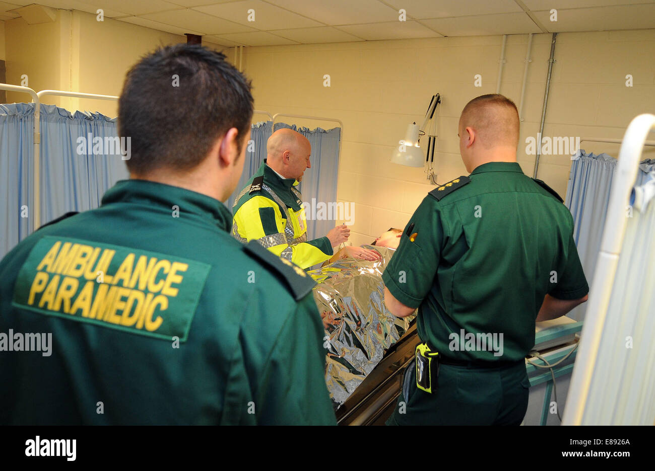 Ambulancia y paramédicos de emergencias y accidentes equipos de NHS en el hospital con un paciente enfermo en una cama. Foto de stock