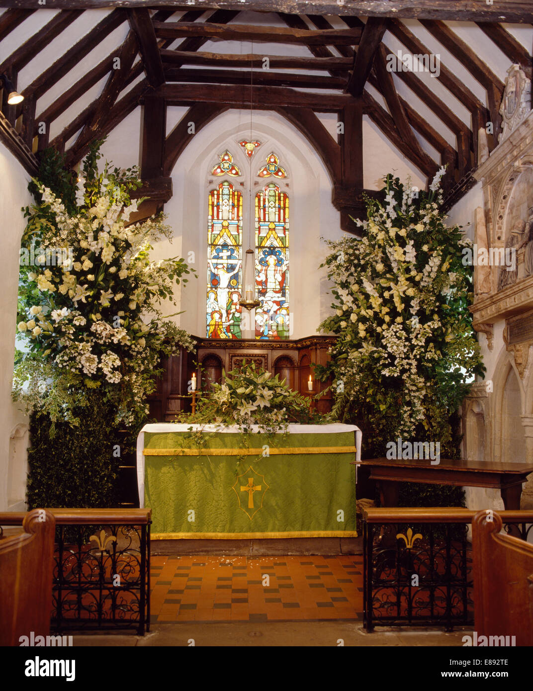 País iglesia decorada para una boda con rosas blancas y lirios en arreglos  florales junto al altar Fotografía de stock - Alamy