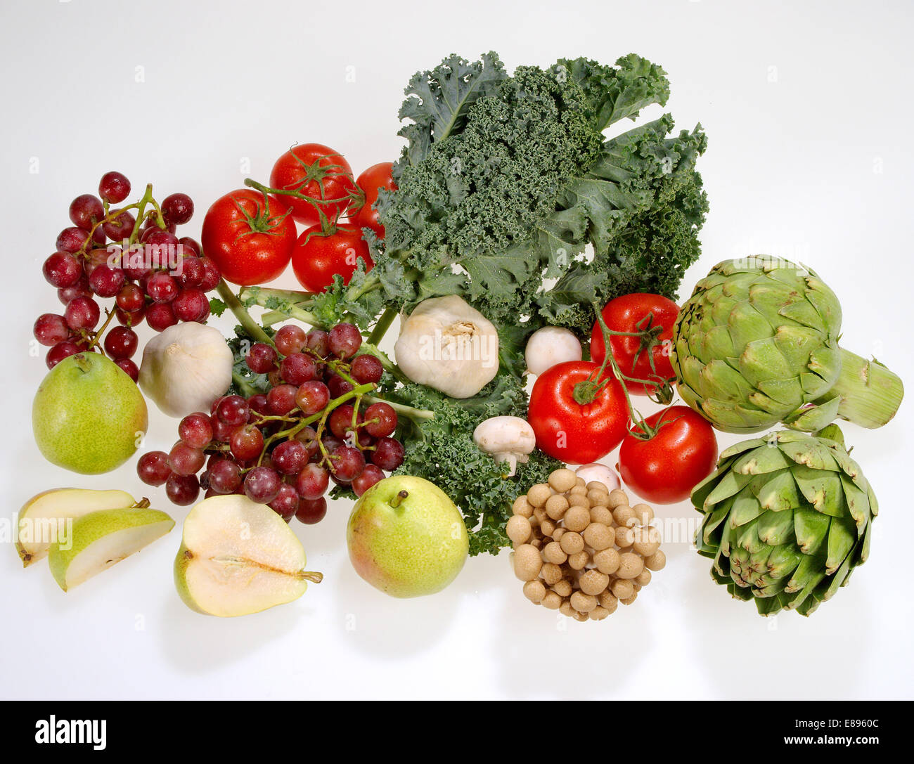 Frutas y hortalizas, incluidas las uvas rojas, rojo tomate, ajo, las alcachofas, las peras de Anjou, la col rizada, frondoso y champiñones. Foto de stock