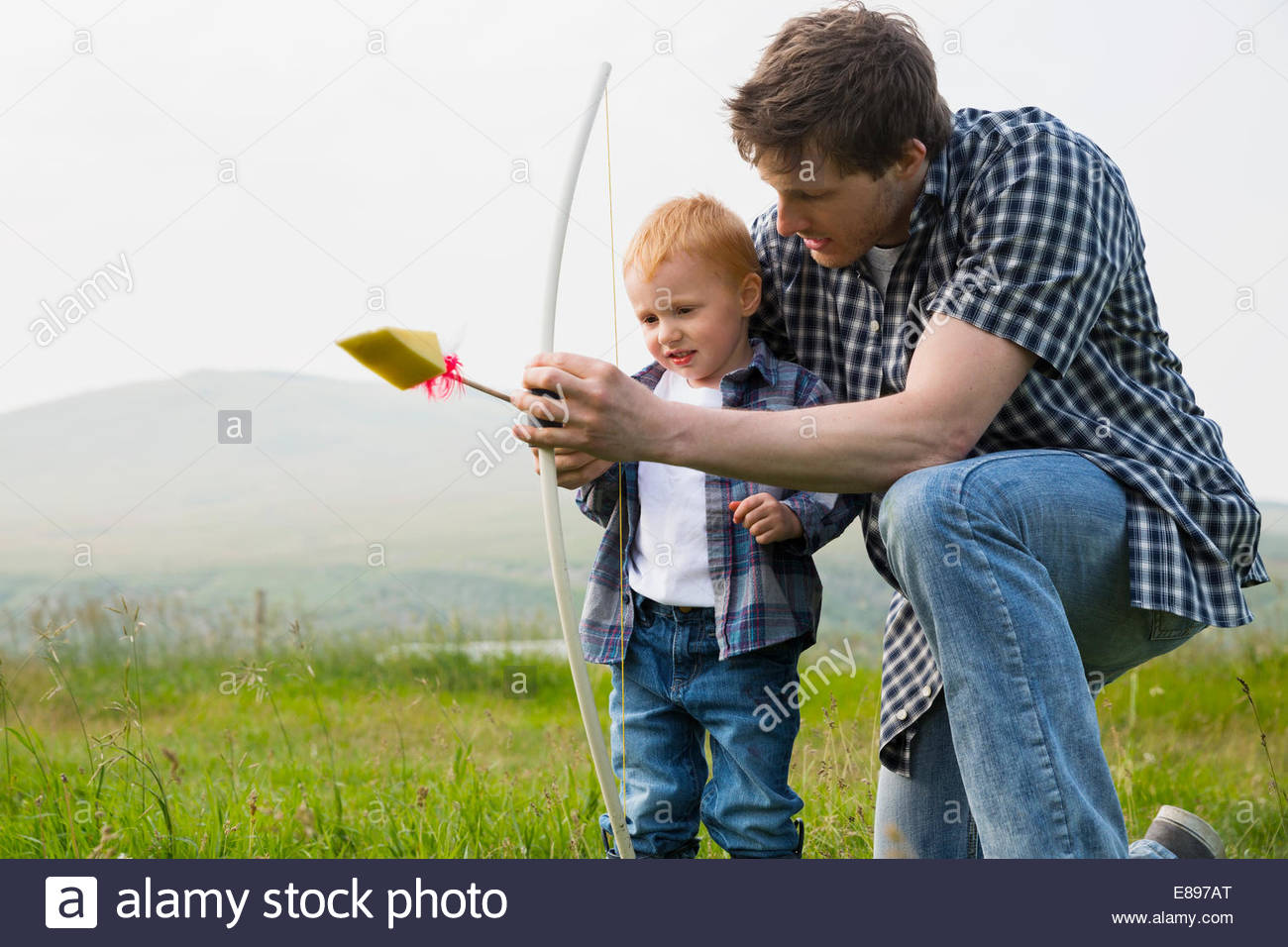 Hijo de padre enseñar a usar arco y flecha Foto de stock