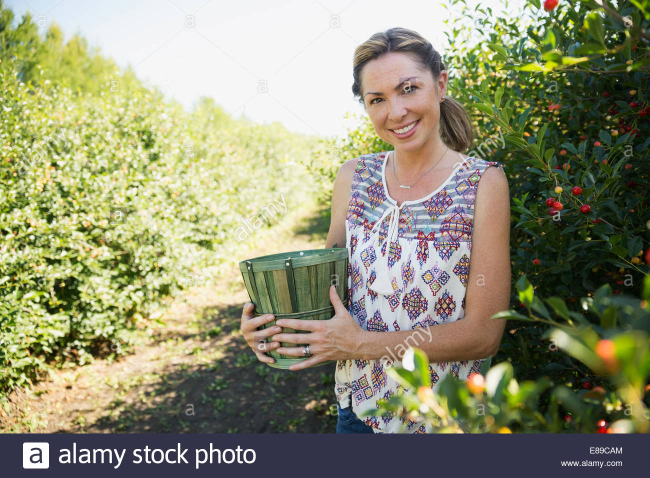 Retrato de mujer sonriente recogiendo las pasas de Corinto en el jardín Foto de stock