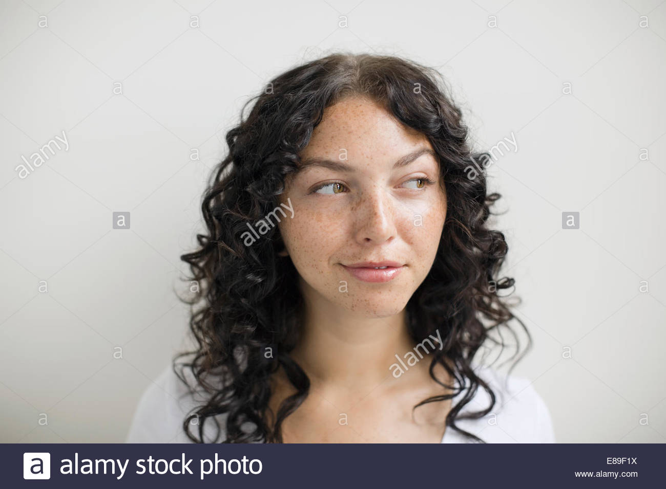 Pensativo mujer con pecas y cabello negro rizado Foto de stock