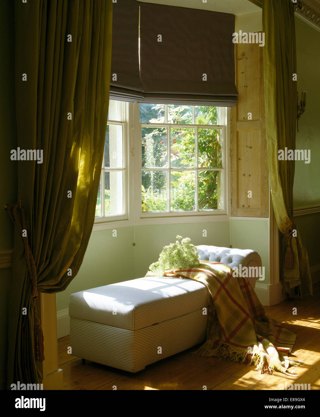 Cortinas de lino y opulentas cortinas de color verde en la ventana de la  habitación encima de una manta blanca con chaiselongue comprobado  Fotografía de stock - Alamy