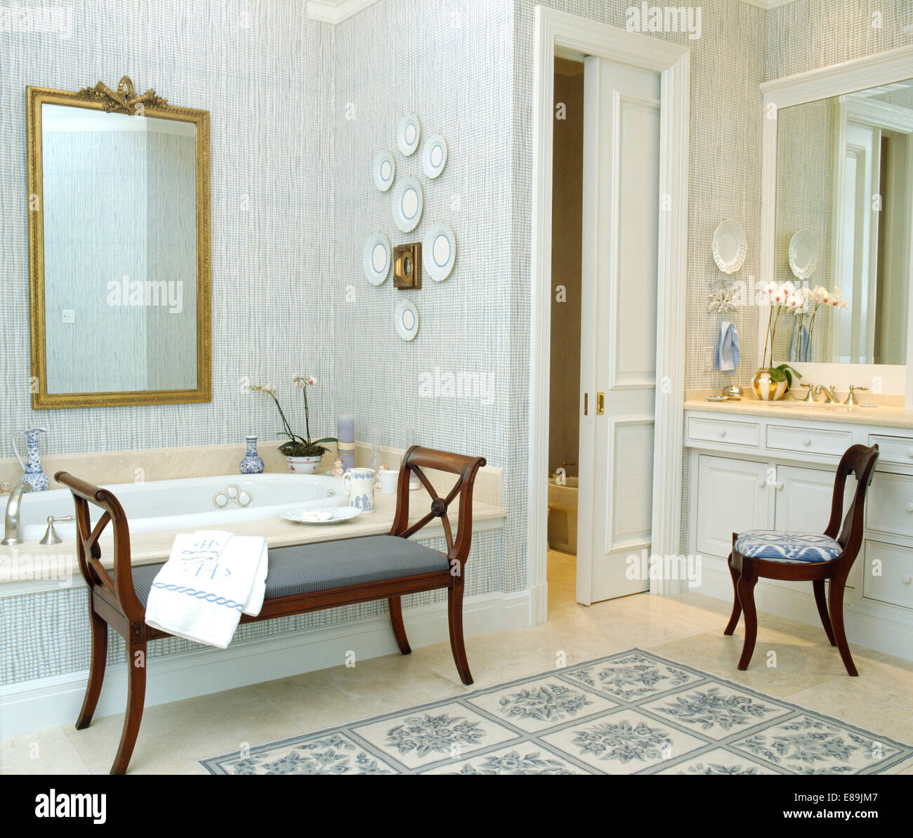 Papel tapiz azul y gran espejo dorado en el cuarto de baño tradicional con  puerta corrediza y antique taburete y silla Fotografía de stock - Alamy