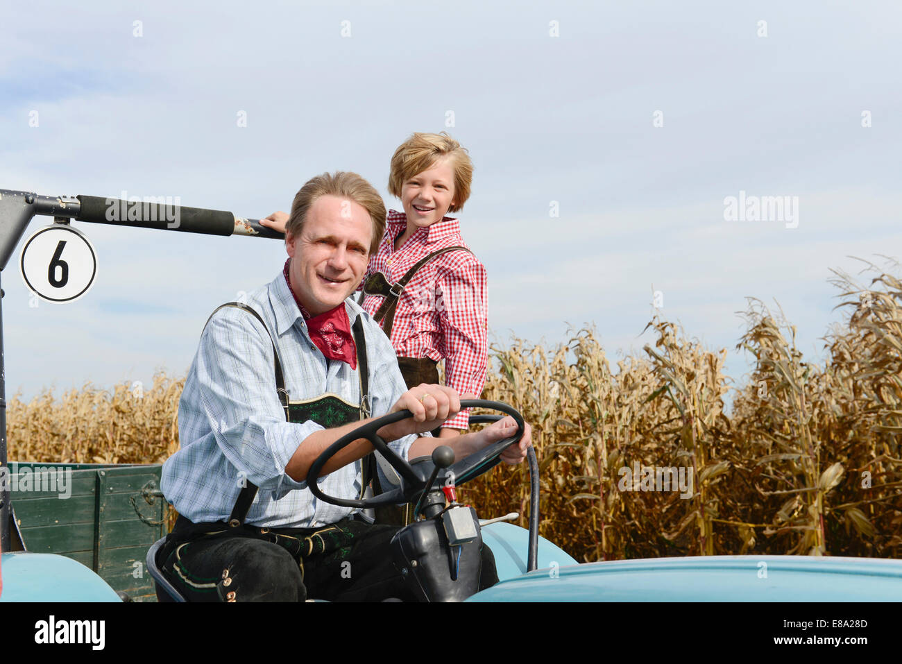 Padre e hijo en el tractor en el maizal, Baviera, Alemania Foto de stock
