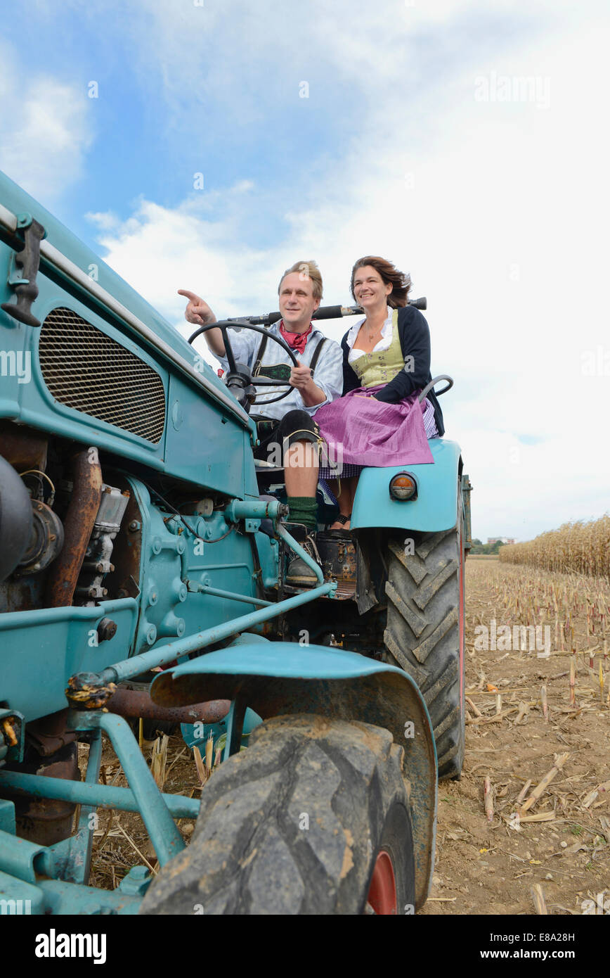 Pareja conduciendo el tractor en el maizal, Baviera, Alemania Foto de stock