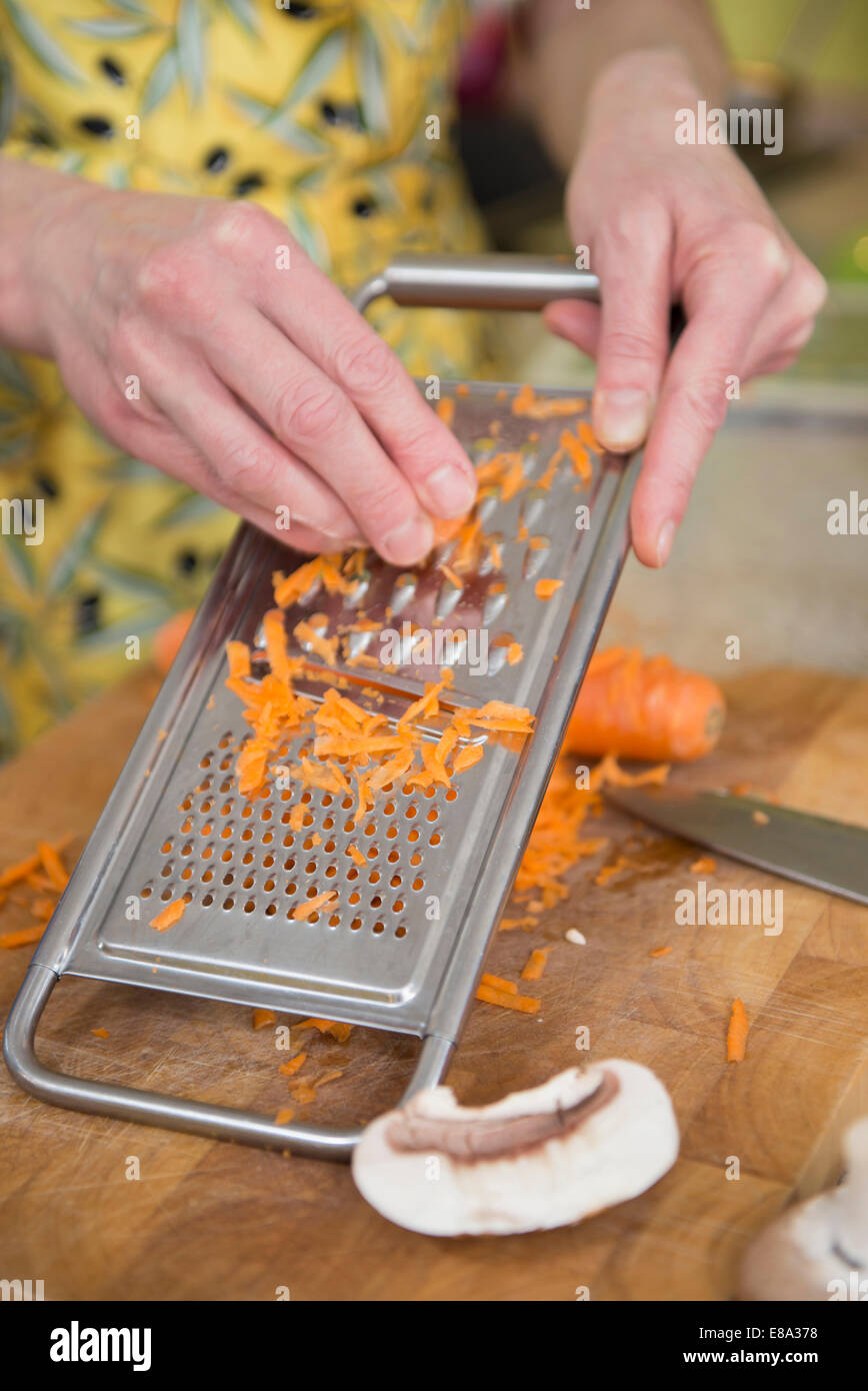 Mujer rallar las zanahorias en la cocina, cerrar Foto de stock