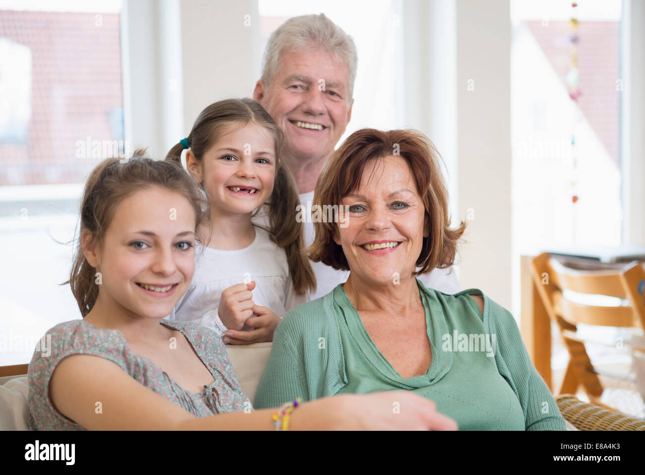 Retrato de abuelos y nietas en salón, sonriendo Foto de stock