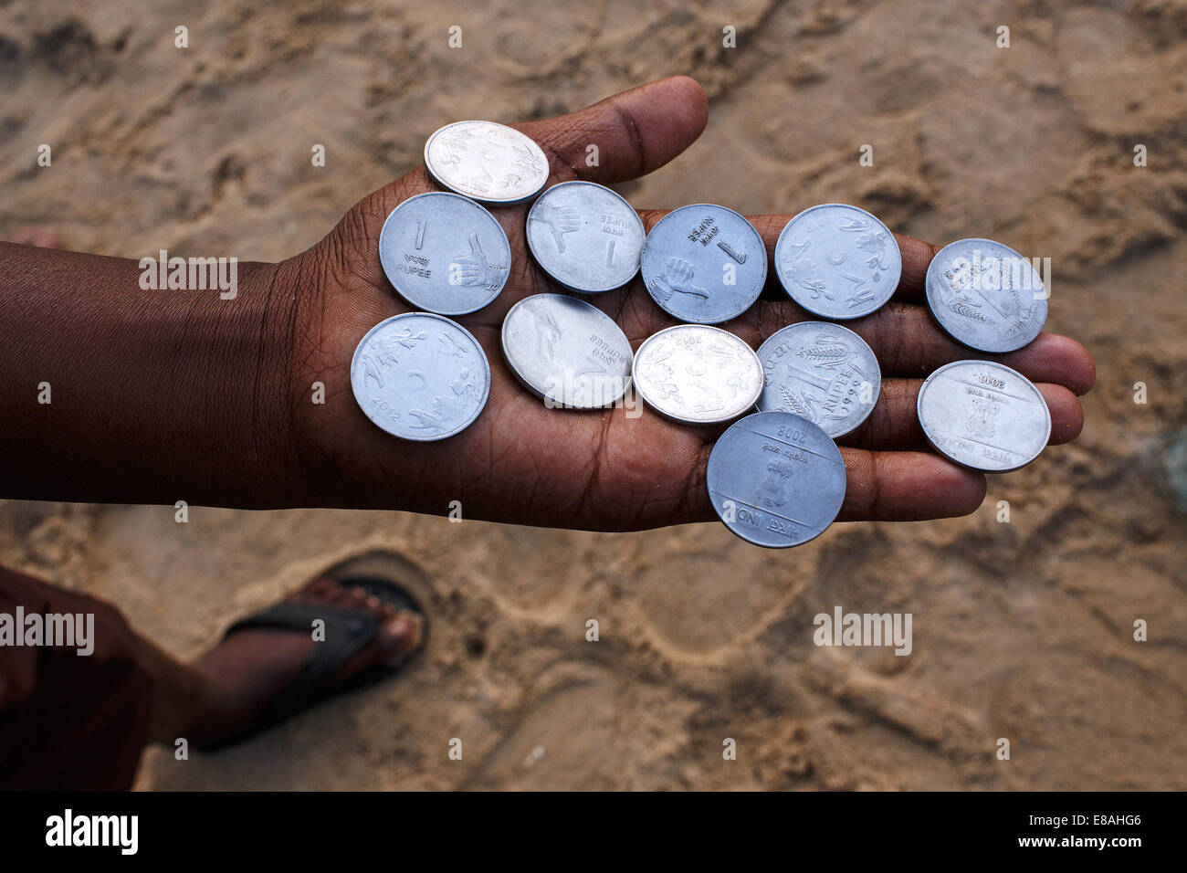 Un joven con Rupias Indias monedas en su mano sobre la playa en Puri, India. Foto de stock