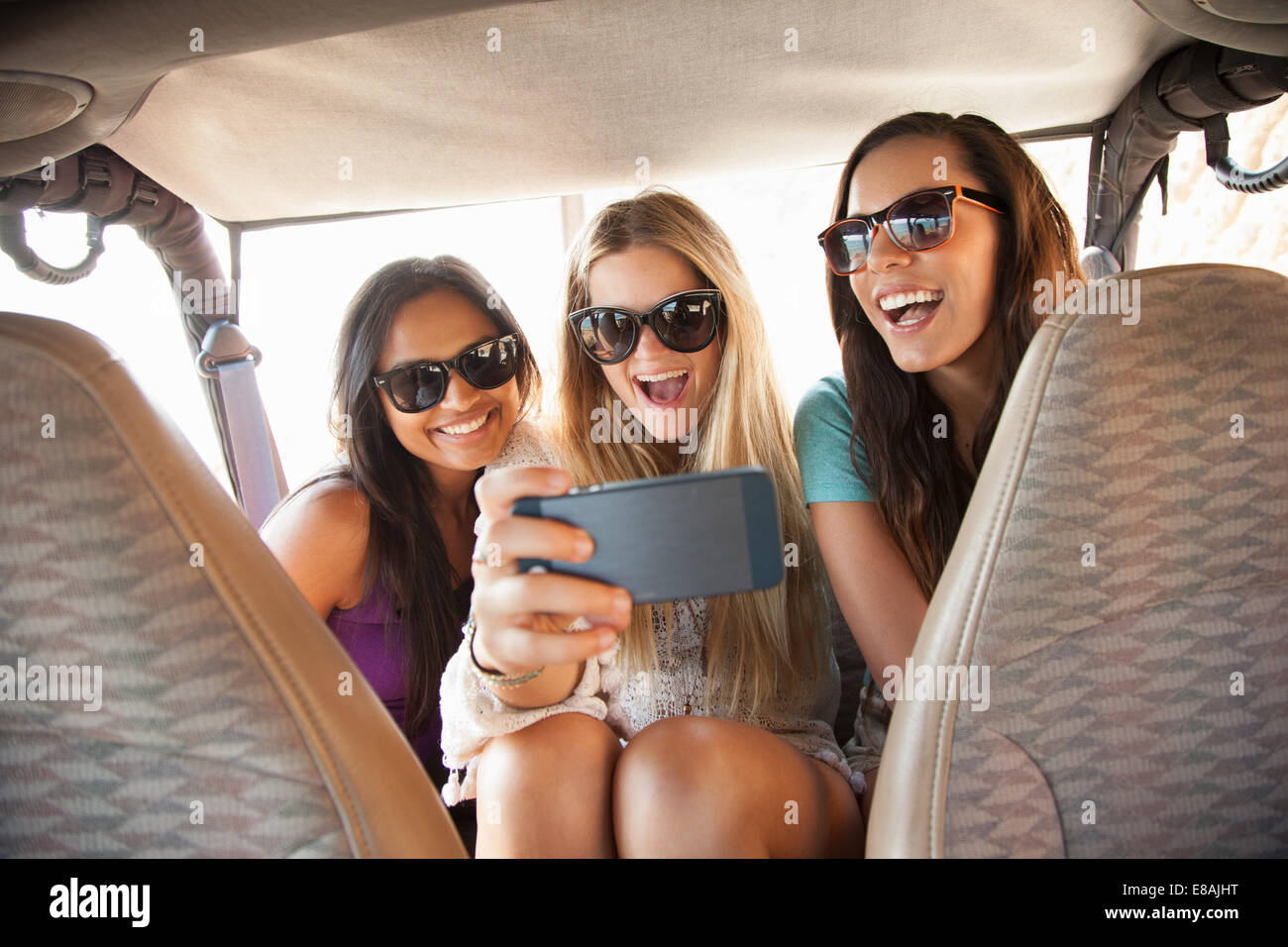 Tres jóvenes mujeres teniendo selfie en smartphone en el asiento de atrás del coche Foto de stock