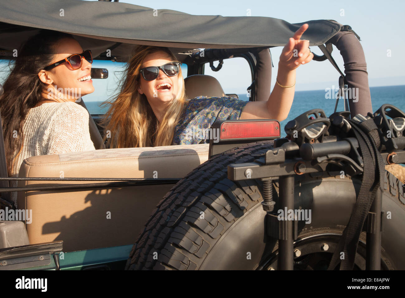 Dos jóvenes mujeres buscando en jeep a costa, Malibu, California, EE.UU. Foto de stock