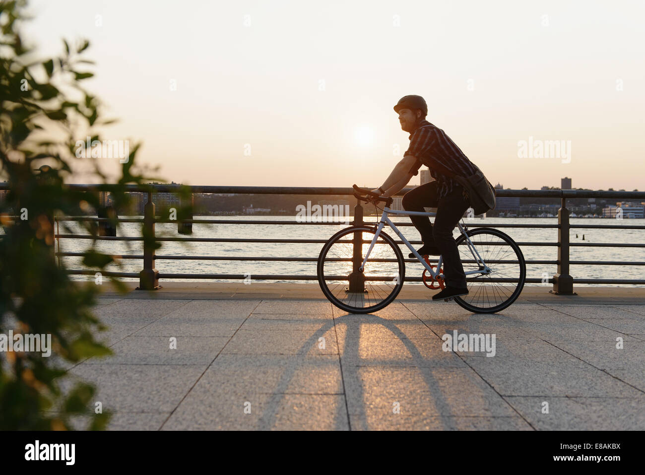 Messenger masculino en bicicleta a lo largo de city riverside Foto de stock
