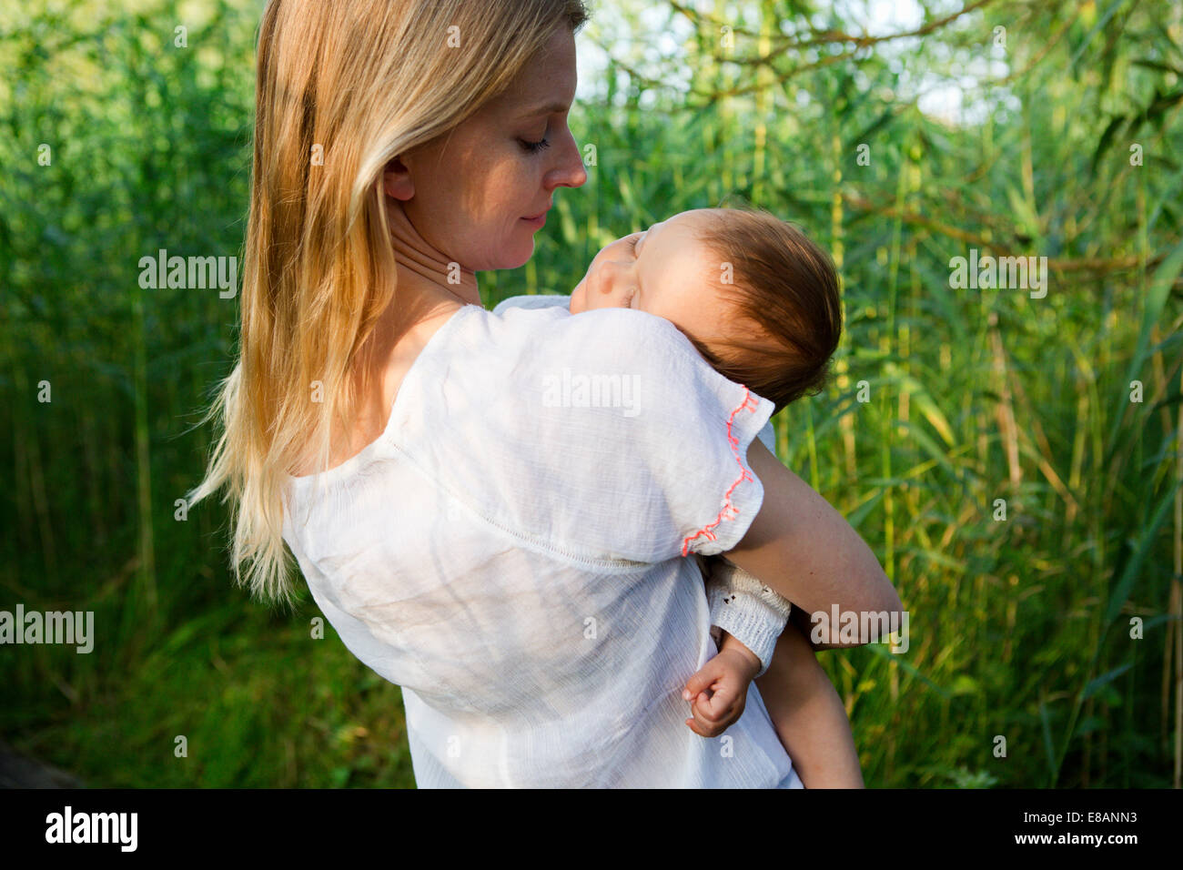 Vista trasera de mediados de adulto y Madre Hija de dormir en el jardín Foto de stock