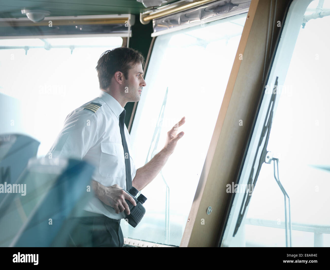 El capitán mirando por la ventana en el puente del barco. Foto de stock