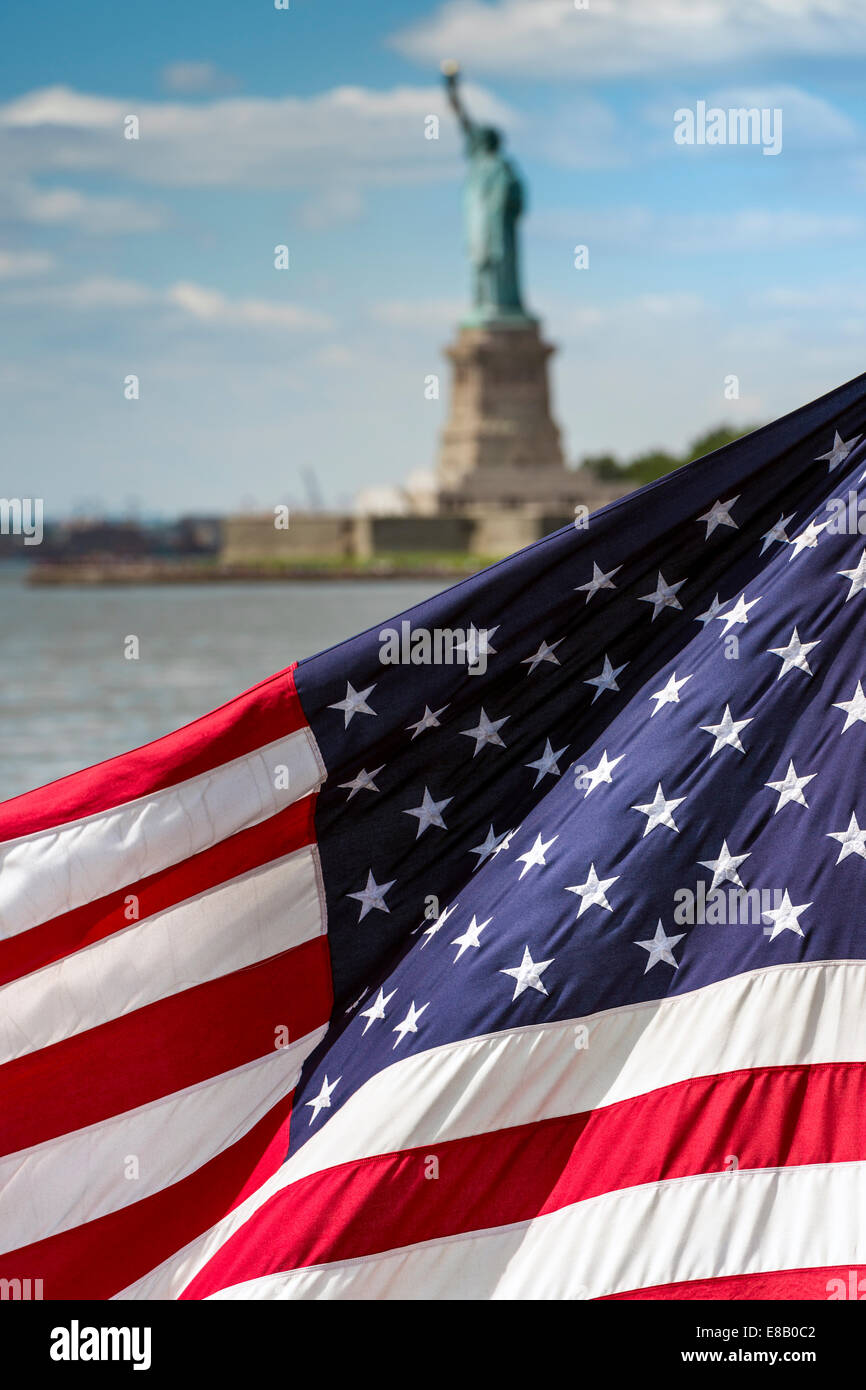 El Star Spangled Banner ondea en la brisa como la Estatua de la libertad constituye el escenario perfecto. Foto de stock
