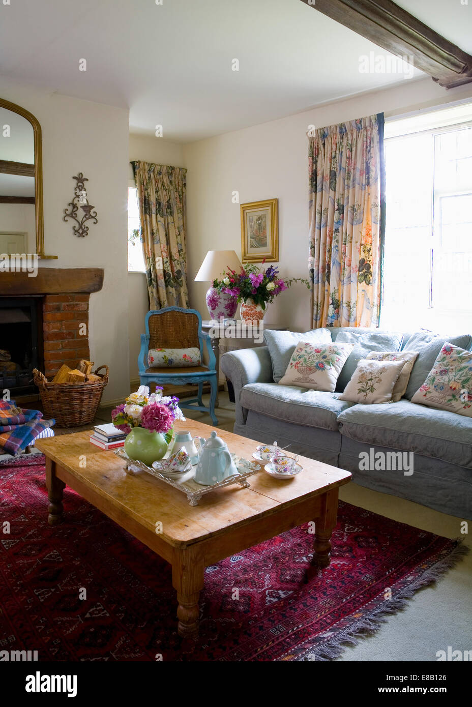 Sofá azul delante de la ventana con cortinas con motivos florales en el  país salón con vintage juego de té en pine mesa de café Fotografía de stock  - Alamy
