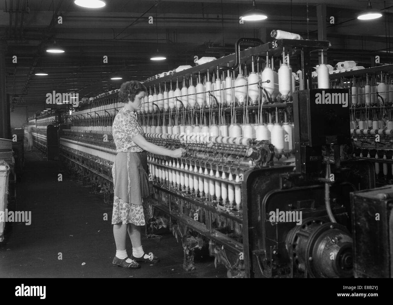 Mujer de pie en la larga fila de bobinas. Millville Manufacturing Co., Nueva Jersey. 1936 Foto de stock