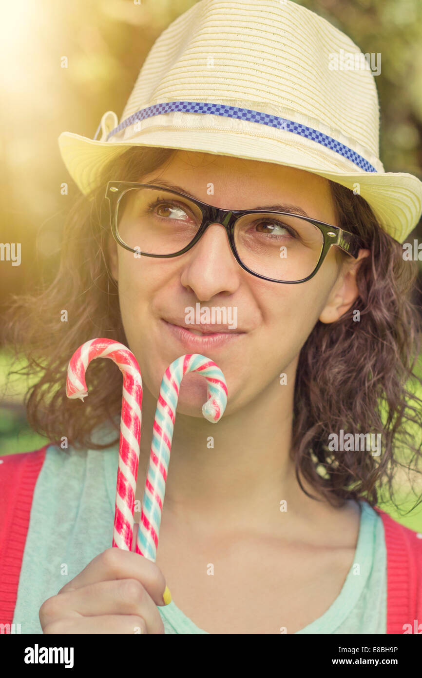 Feliz Hipster adolescente pensando de dulces y sosteniendo bastones de caramelo. outdoor shot, colores retro Foto de stock