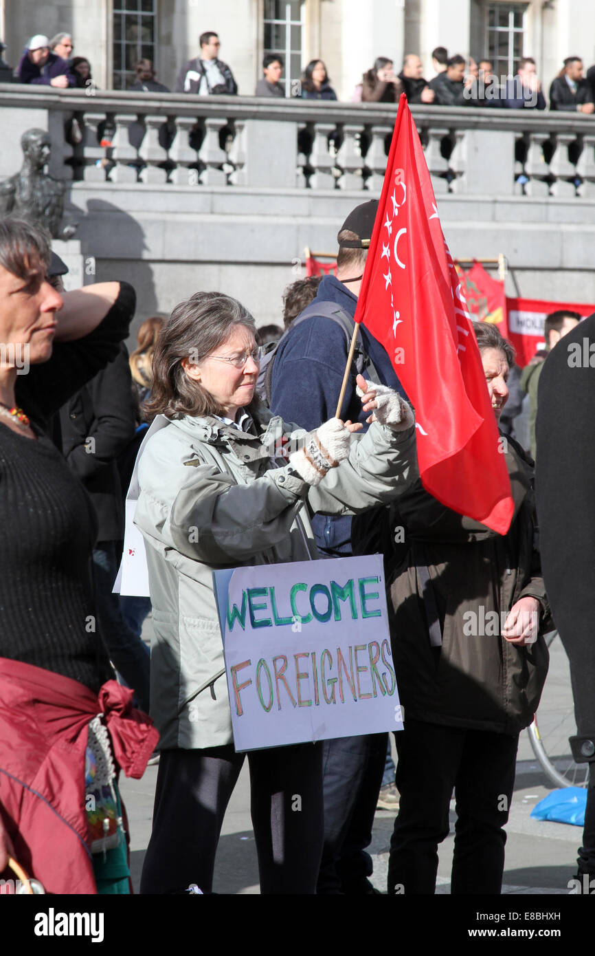 Una mujer sostiene un cartel que decía "Bienvenidos extranjeros" durante una manifestación en la Plaza de Trafalgar de Londres para conmemorar el Día Contra el Racismo de la ONU de 2014 Foto de stock