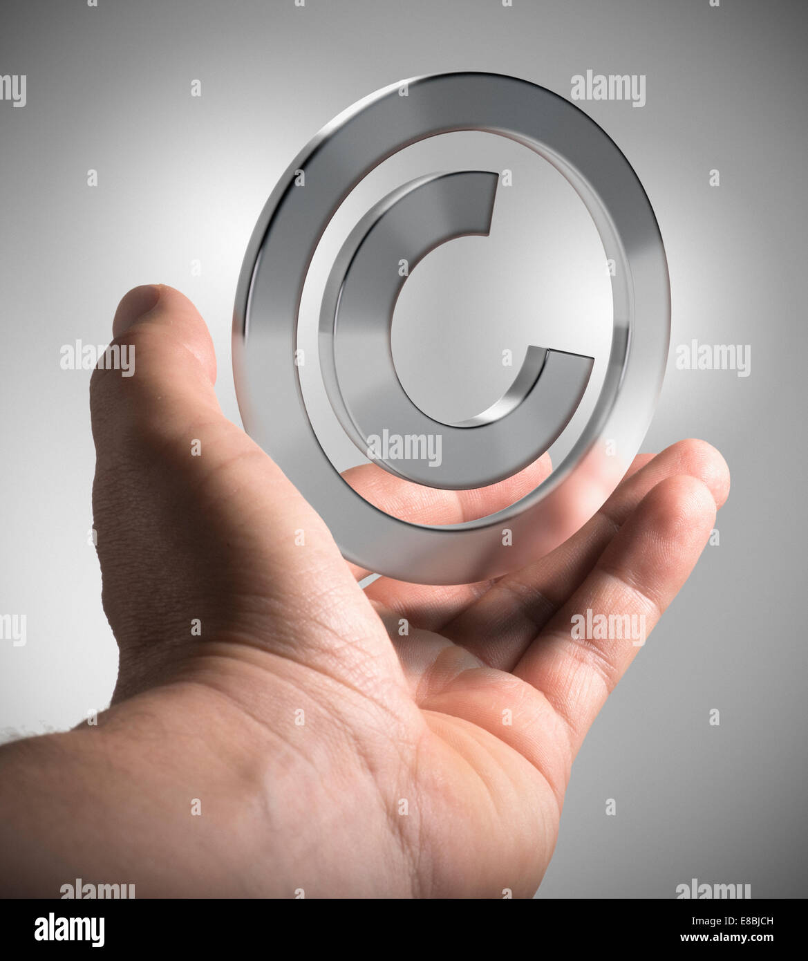 Mano de hombre sosteniendo el símbolo de copyright sobre fondo gris, concepto imagen para ilustración de la propiedad intelectual. Foto de stock