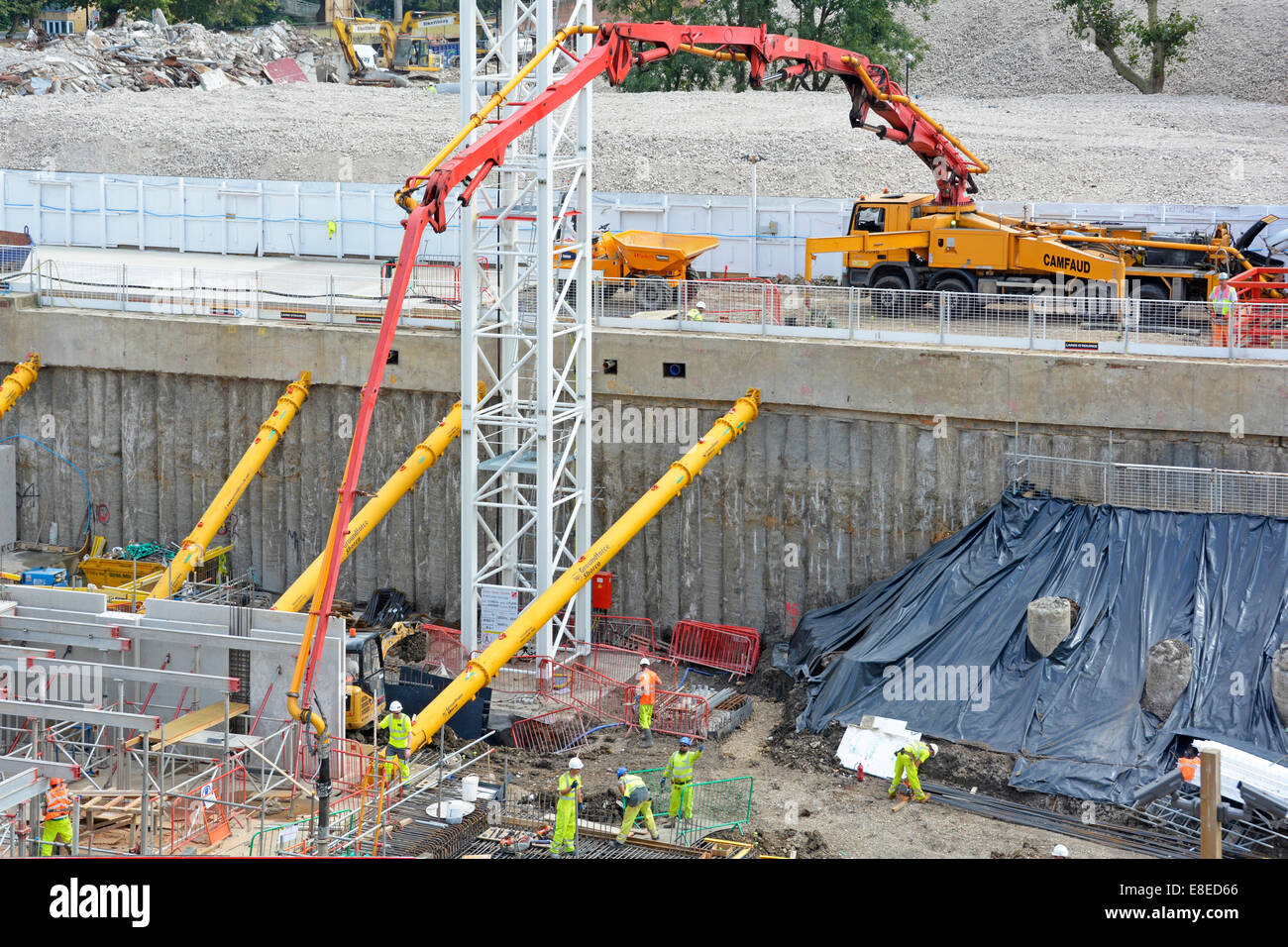 Bombeo de hormigón a la fundación del sótano alrededor de los puntales de apuntalamiento hidráulico amarillo para apilados de construcción de muros de retención sitio de construcción Londres Inglaterra Reino Unido Foto de stock