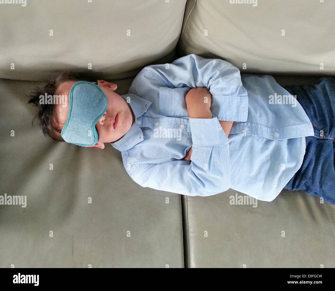 Niño acostado en un sofá con máscara para los ojos Foto de stock