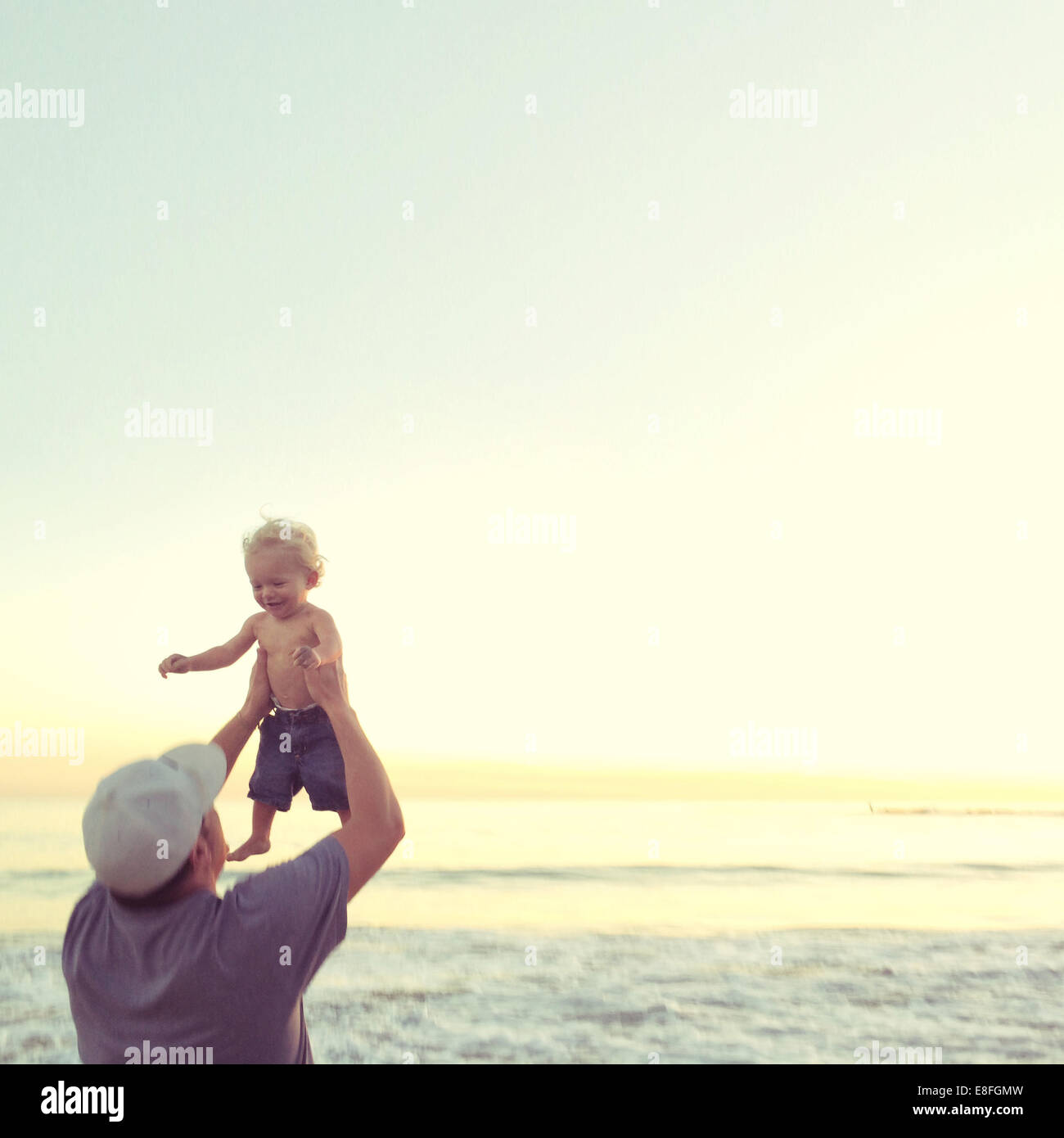 Padre levantando a su hijo en el aire en la playa, California, Estados Unidos Foto de stock