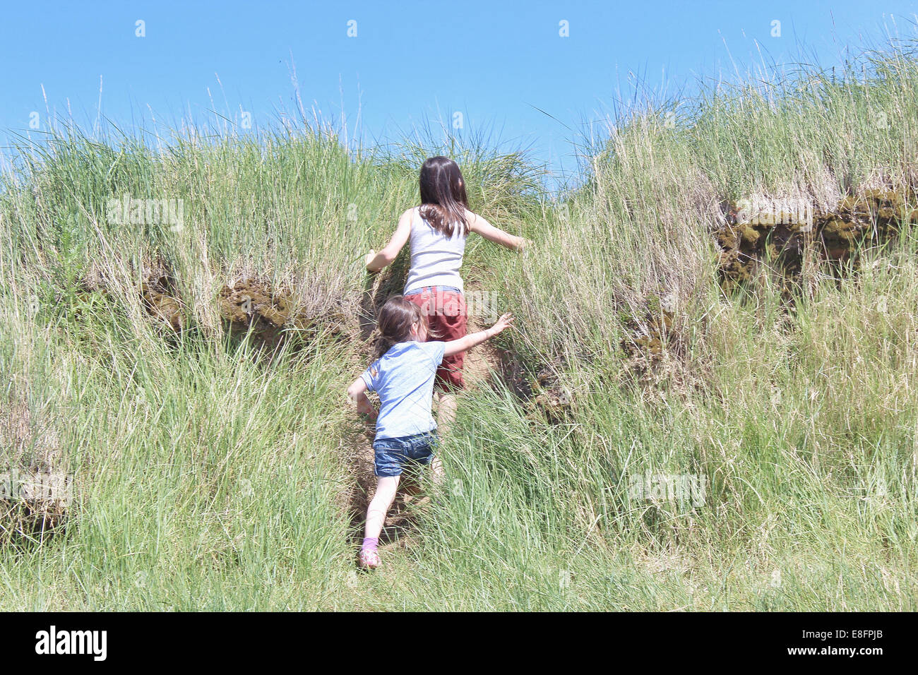 Vista trasera de dos niñas subiendo una colina Foto de stock