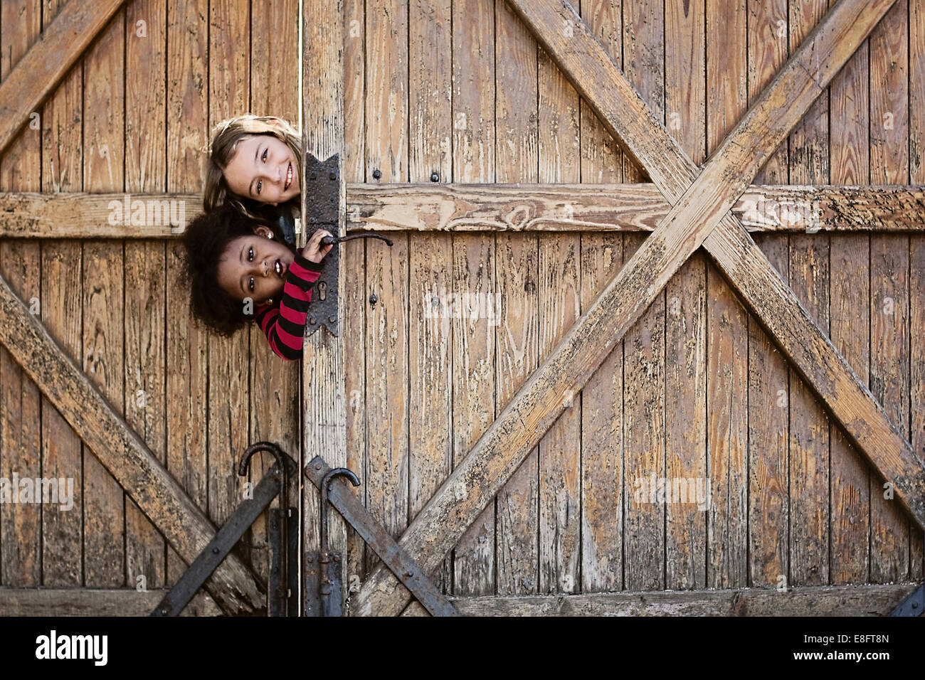 Dos niñas mirar una puerta de madera redonda Foto de stock