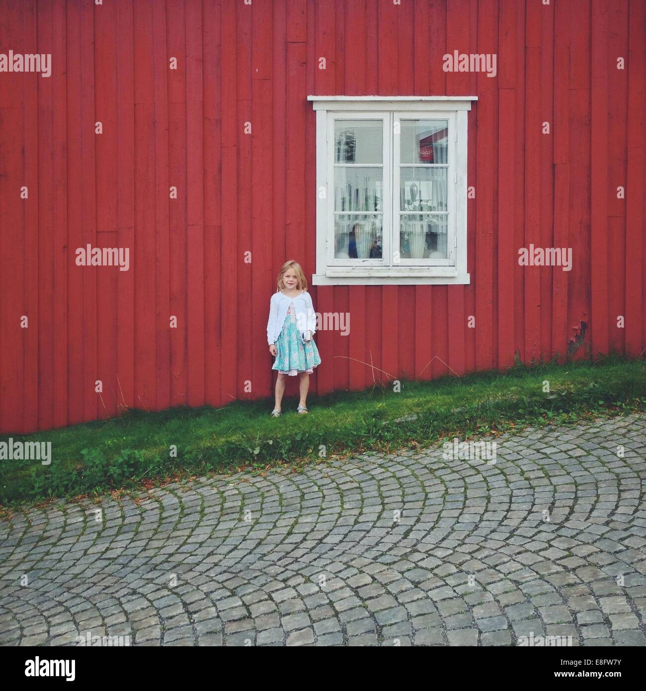 Noruega, Chica (12-13) de pie contra la casa roja Foto de stock