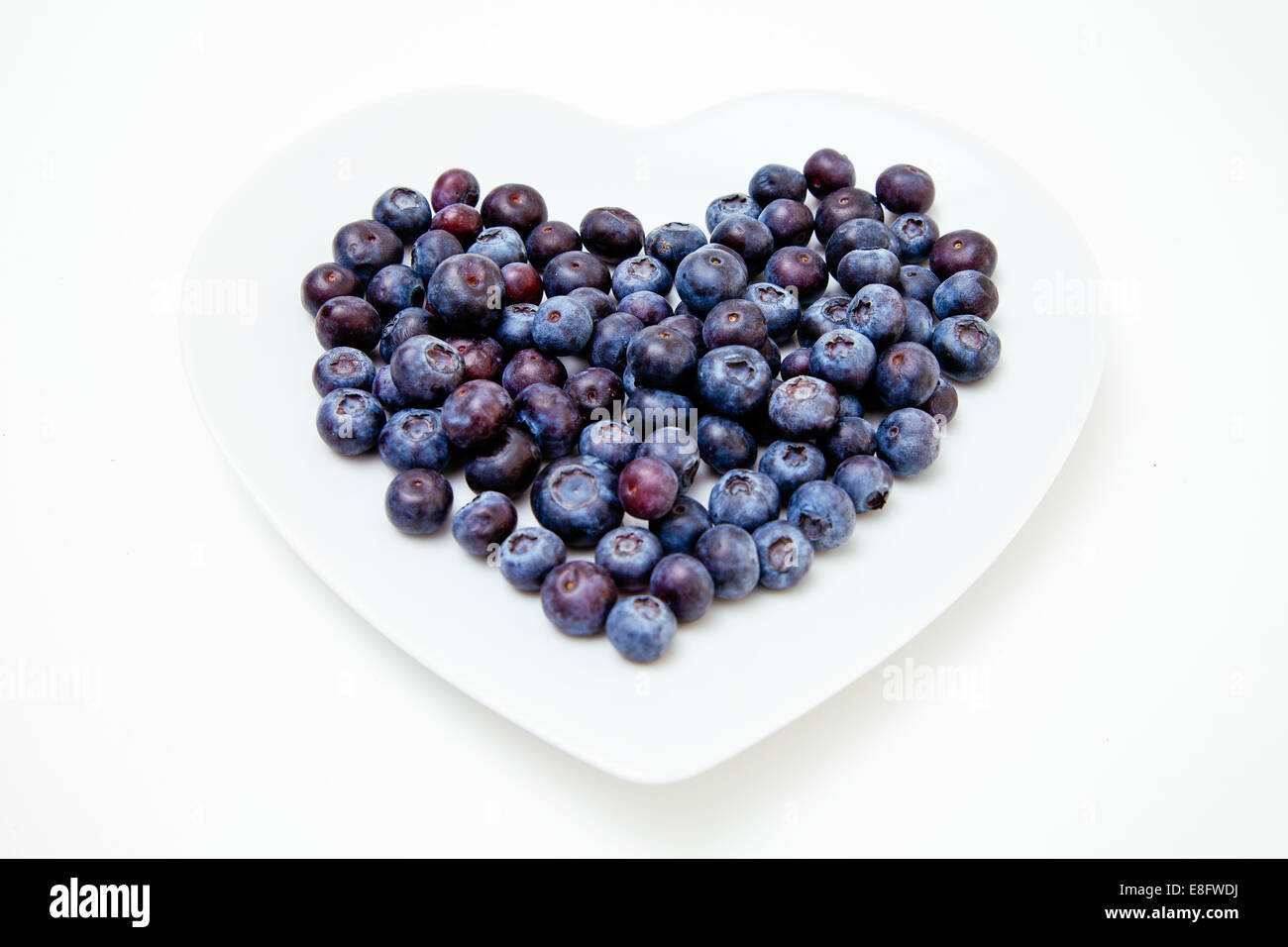 Primer plano de arándanos frescos sobre un plato en forma de corazón Foto de stock