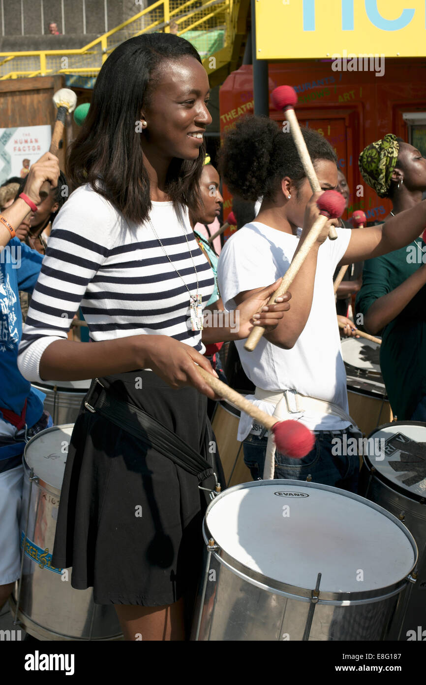 Sonriendo bastante joven baterista femenina en un desfile en un día soleado, South Bank de Londres, Inglaterra Foto de stock
