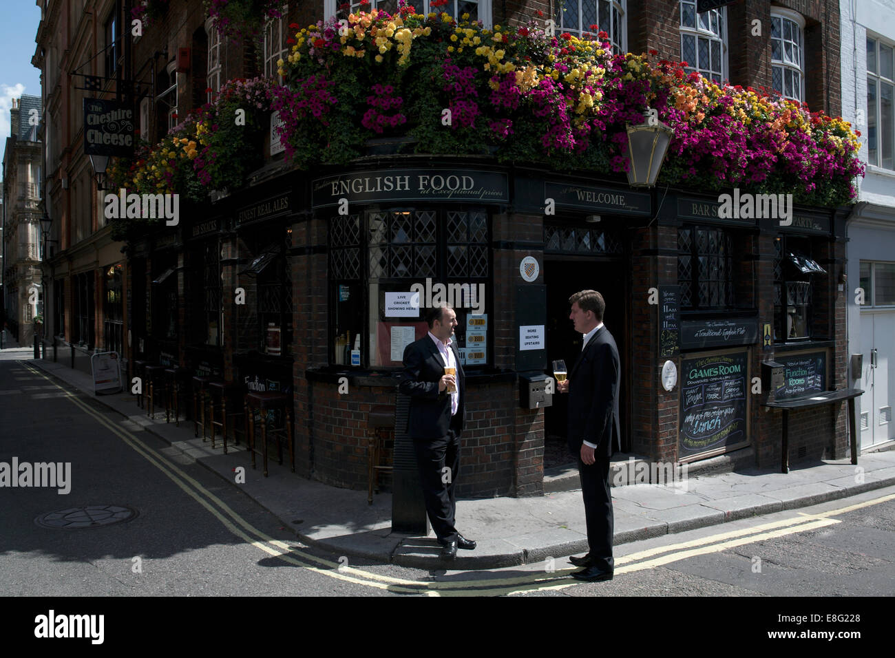 Dos hombres que ocupan las bebidas hablando fuera de un pub public house día soleado, esquina de la calle Londres England Reino Unido cartel que decía comida inglesa Foto de stock