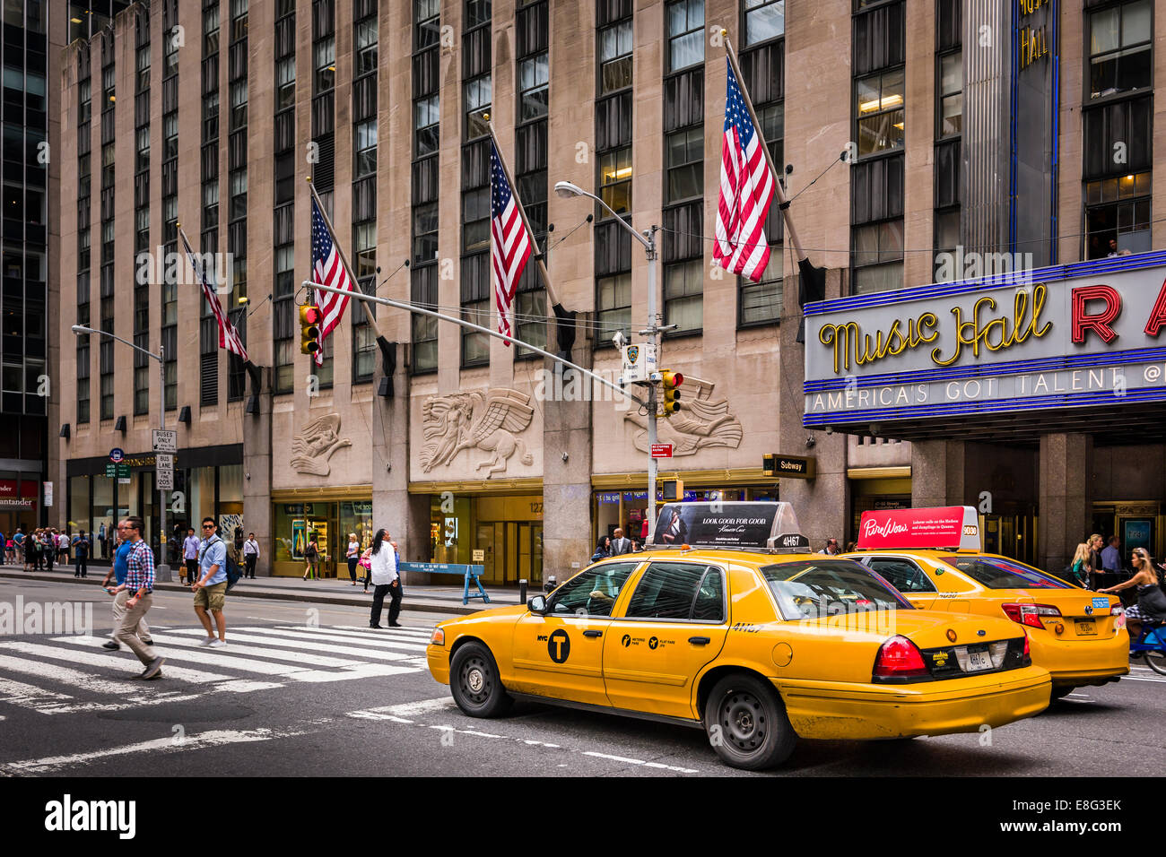 Un taxi amarillo de Nueva York espera para que los peatones crucen fuera del Radio City Music Hall en Manhattan. Foto de stock
