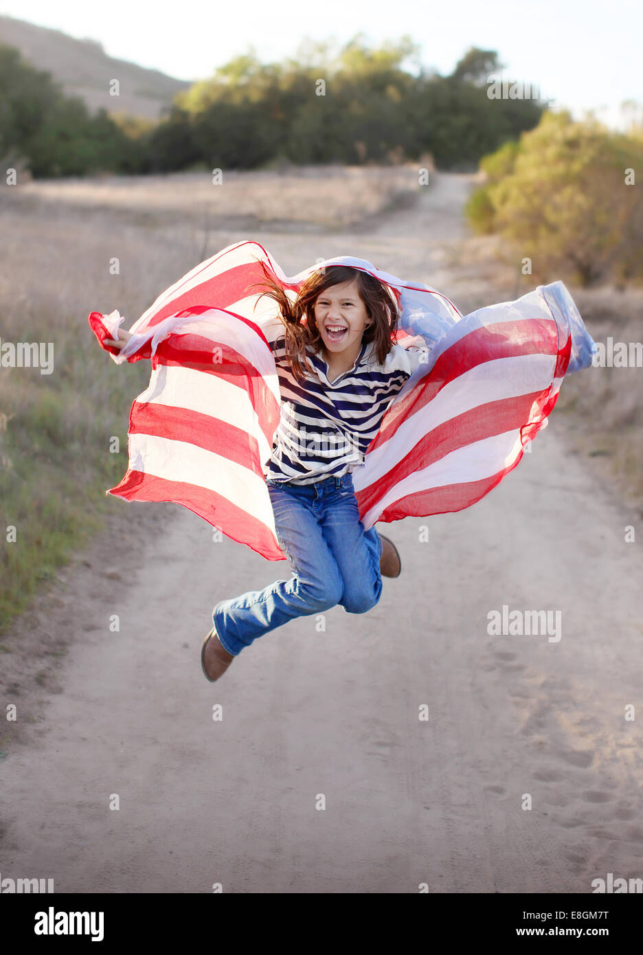 Chica saltando en el aire sosteniendo la bandera americana Foto de stock