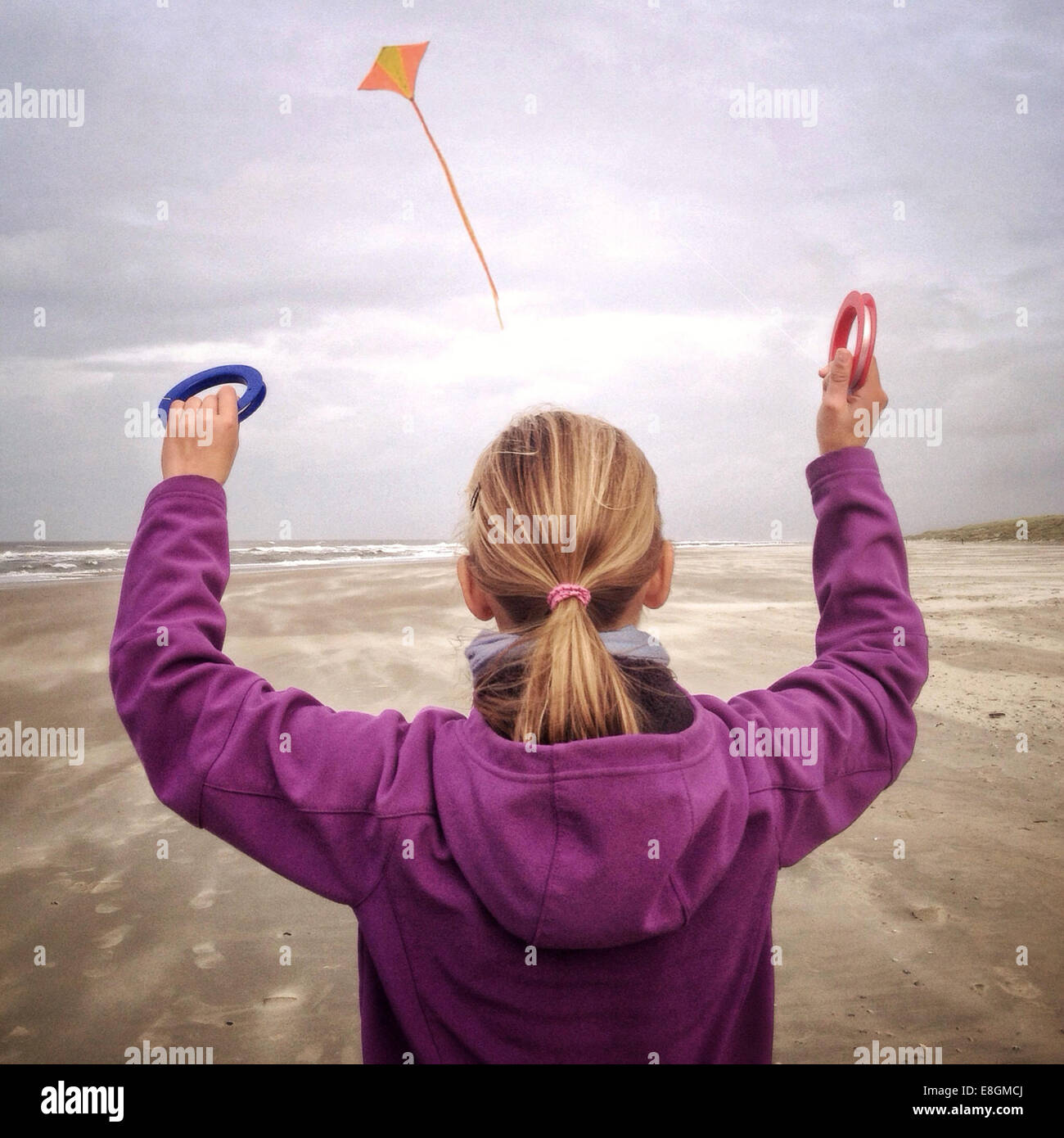 Vista trasera de la chica volando cometa en la playa Foto de stock