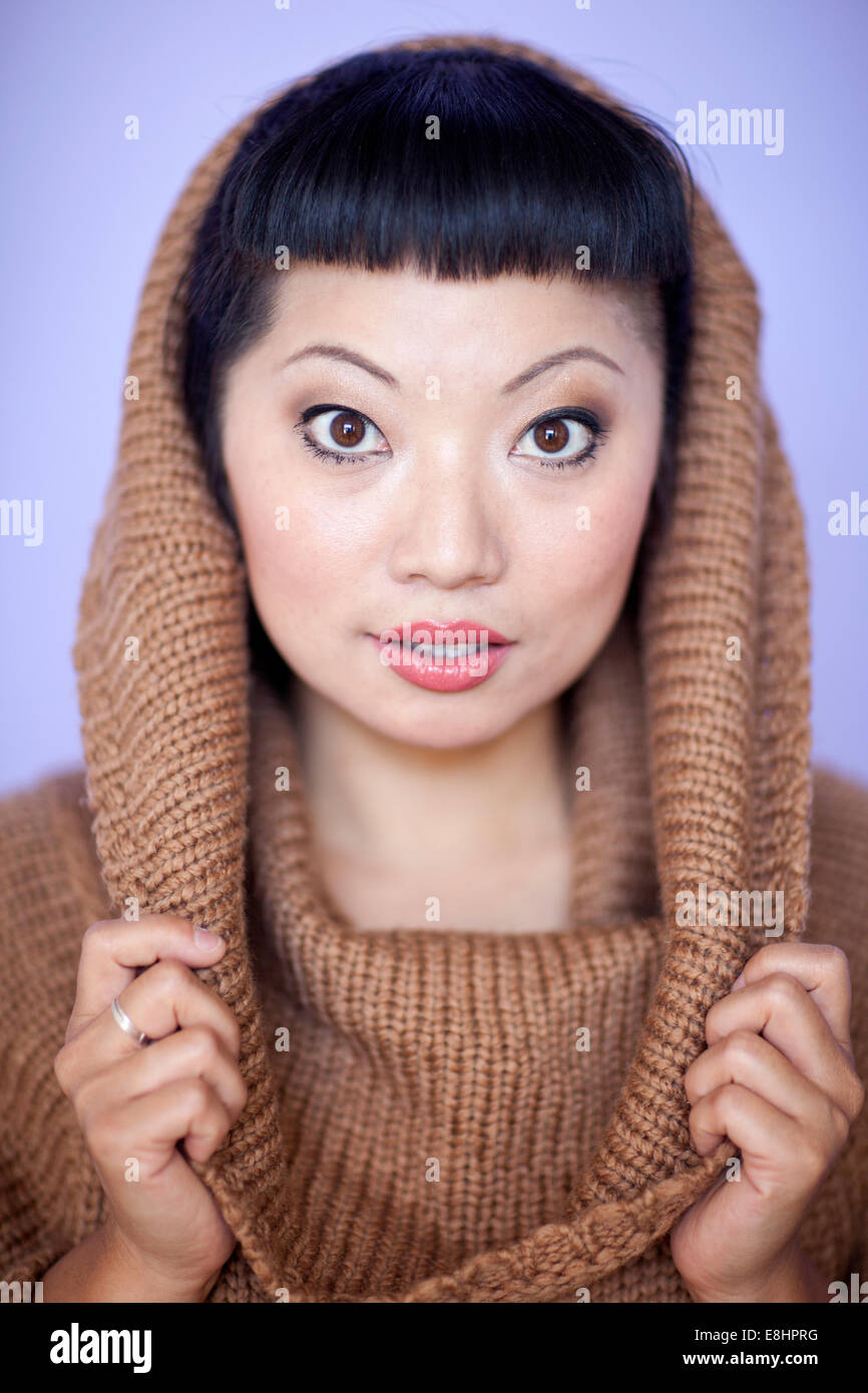Mujer asiática con cálidos fuzzy suéter de cuello del salpicadero. Corte de pelo corto con flequillo lindo. Foto de stock